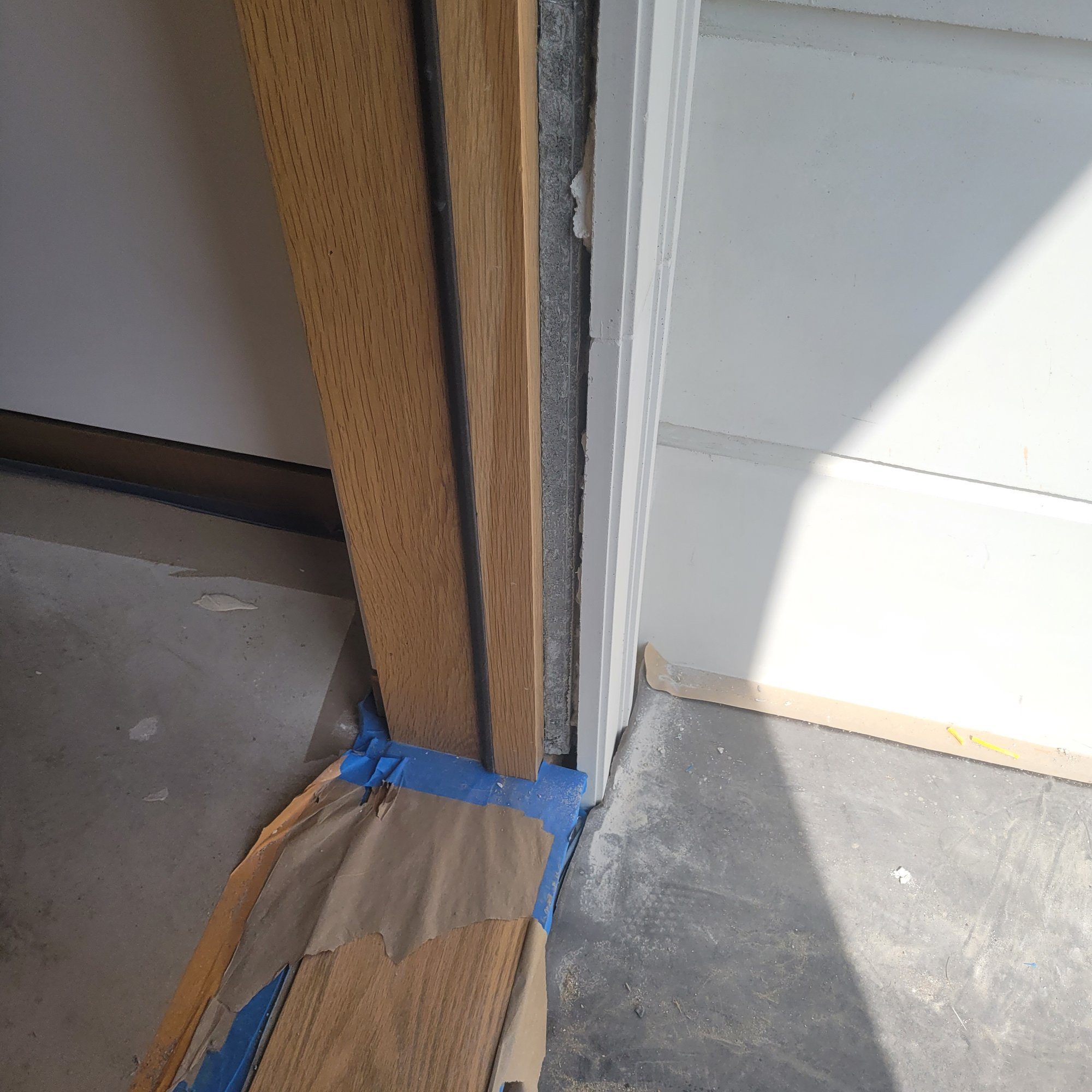 A new wood door jamb meeting painted trim, with the threshold covered.