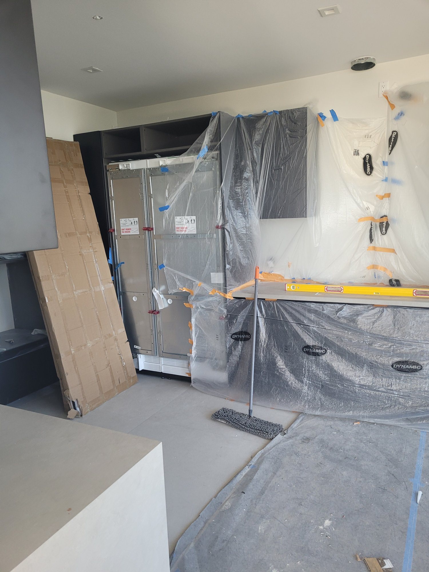 Panel-ready refrigerator columns and cabinets under protective film during installation.