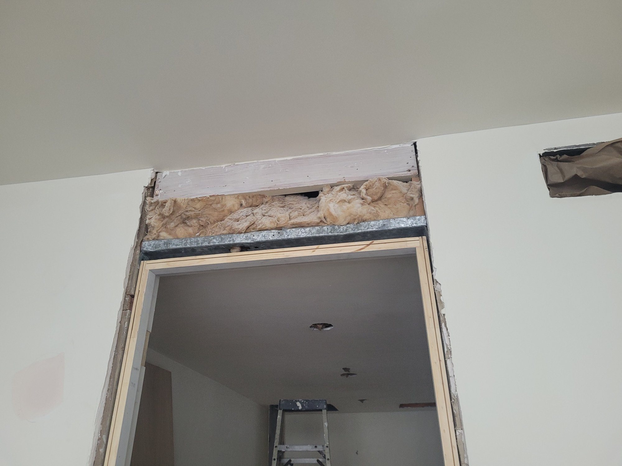 An opening in an existing wall, reframed with a steel track and a new wood jamb.