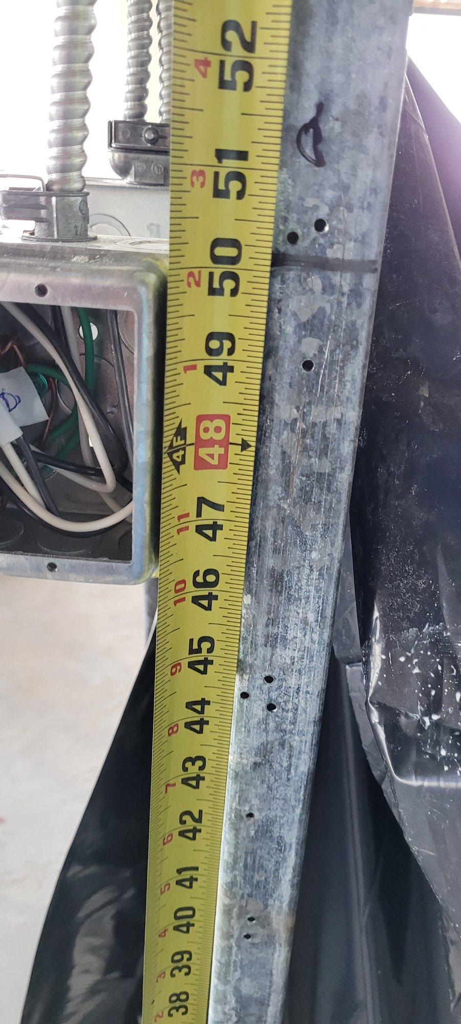 Checking the height of a new electrical box against a steel stud.